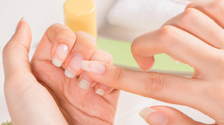A woman rubbing cuticle oil on hands