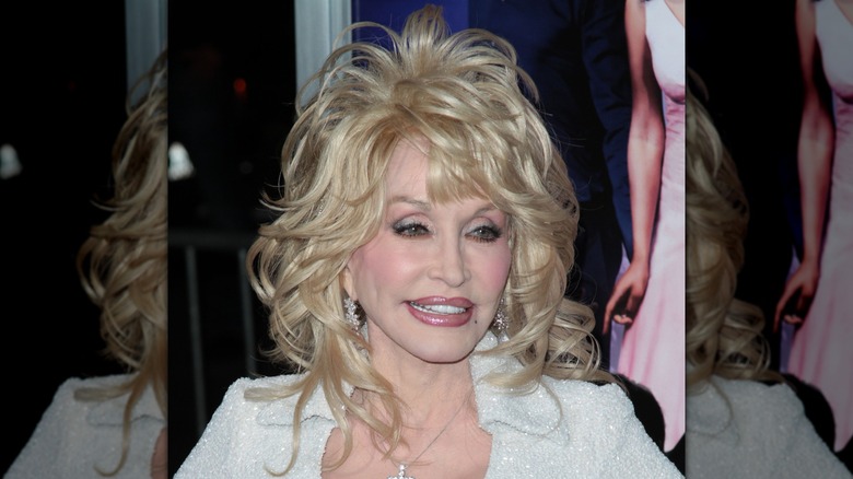 Dolly Parton smiling while wearing a tousled, blond wig