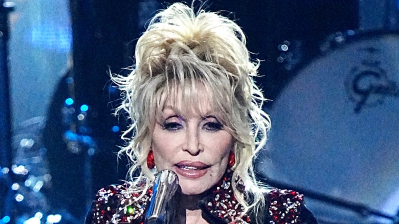 Dolly Parton performing on stage with a messy, wavy updo in 2022