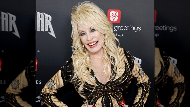 Dolly Parton smiling on the red carpet with a shaggy, blond wig
