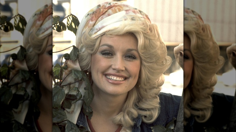 Dolly Parton smiling while wearing a headscarf in a 1977 headshot photo