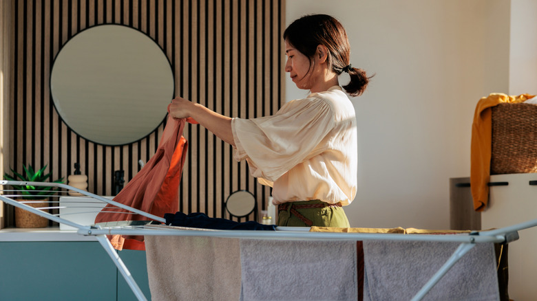 Woman folding laundry over drying rack