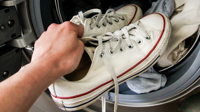 A person putting converse into a dryer drum