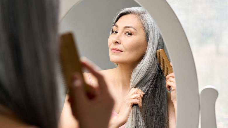 Woman combs hair in mirror