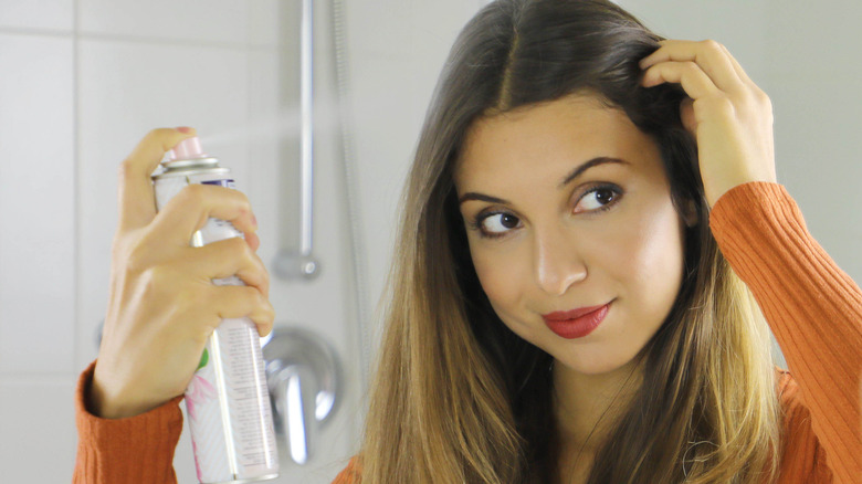 Woman spraying dry shampoo into hair