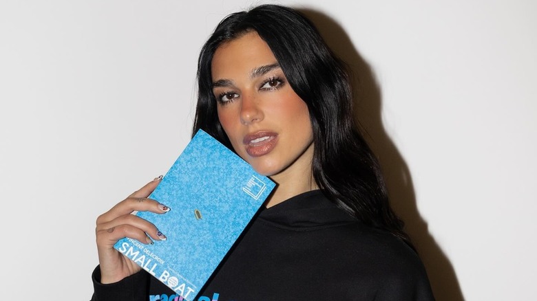 Dua Lipa holding the book Small Boat by Vincent Delecroix