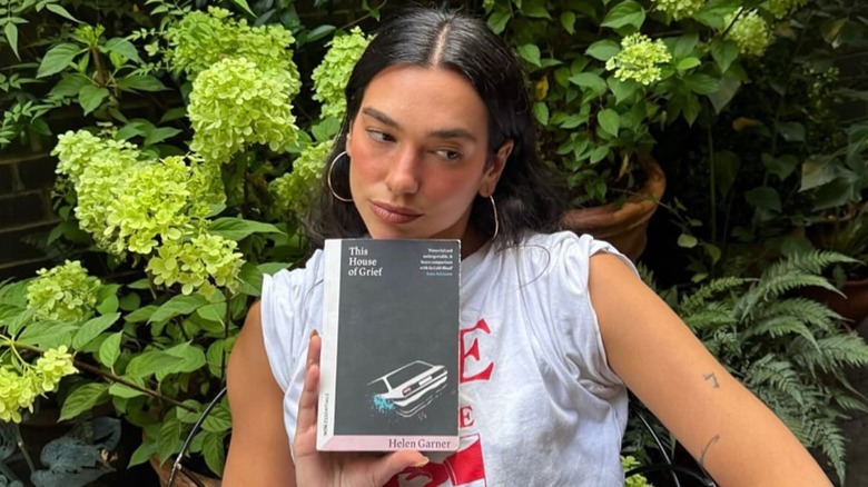 Dula Lipa holsing a copy of This House of Grief: The Story of a Murder Trial by Helen Garner