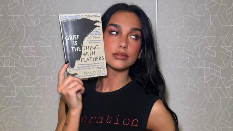 Dua Lipa holding a copy of Grief Is the Thing with Feathers by Max Porter