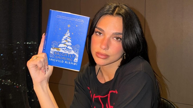 Dua Lipa holding a copy of Brightly Shining by Ingvild Rishøi