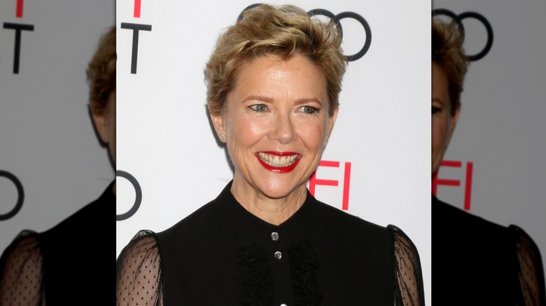Annette Bening wearing a red lipstick and two gold studs