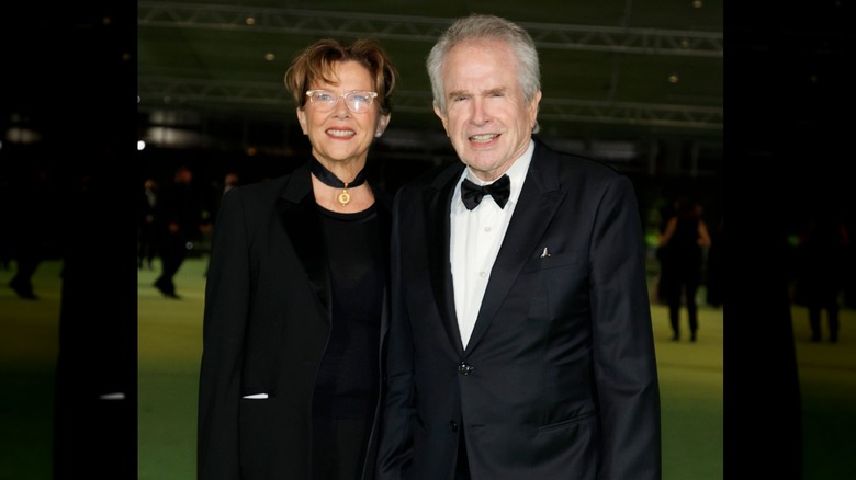 Annette Bening wearing black suit and and light pink lipstick next to husband Warren Beatty