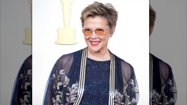 Annette Bening wearing a blue sequin jacket and orange glasses
