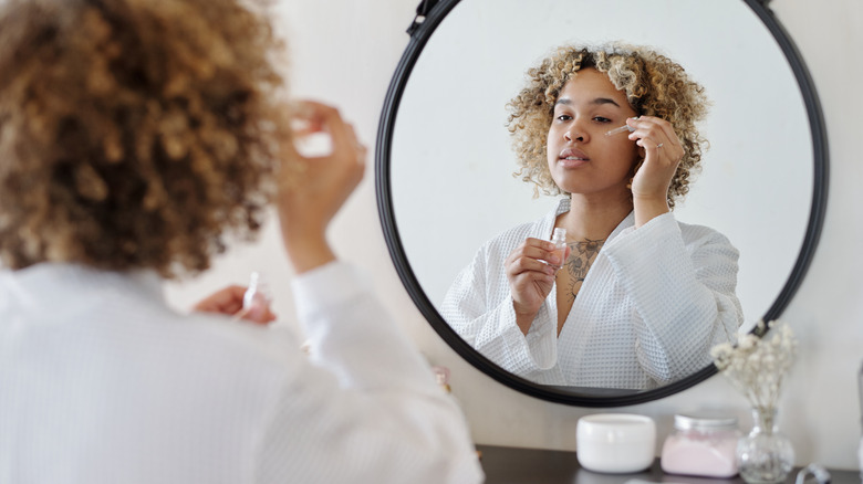 woman applying serum to face