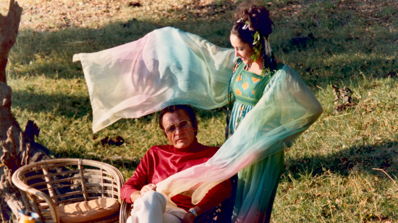 Elizabeth Taylor waving the flowy sleeves of her tie-dye dress around husband Richard Burton
