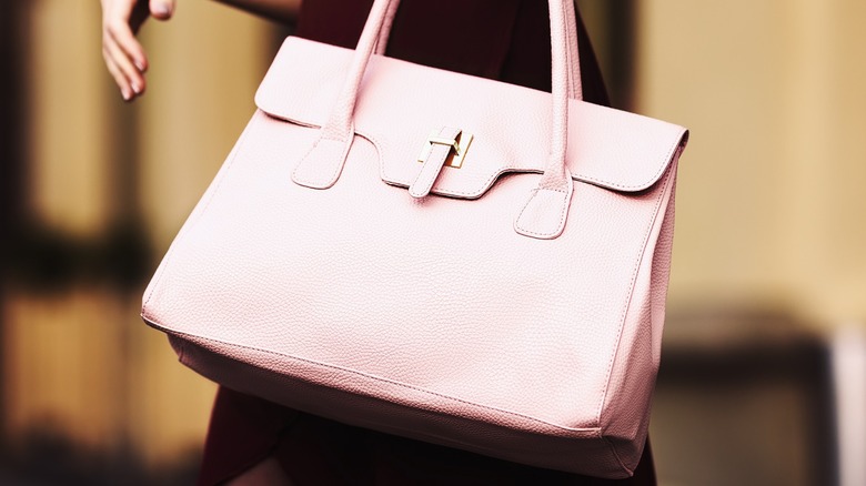 Woman wears large pink handbag