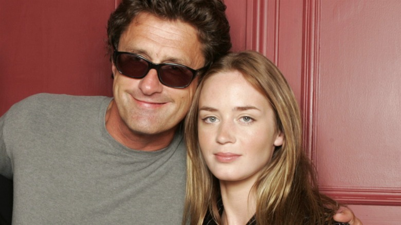 Young Emily Blunt posing with director Pawel Pawlikowski in front of a red wall