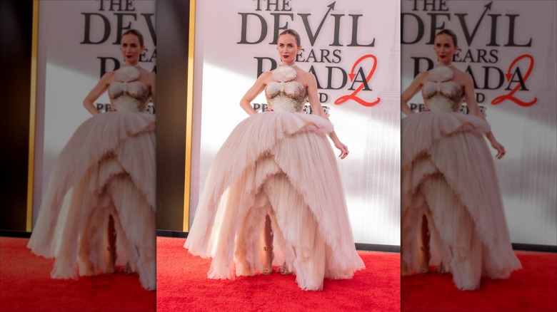 Emily Blunt smiles wearing a ballgown dress featuring a layered tutu skirt.