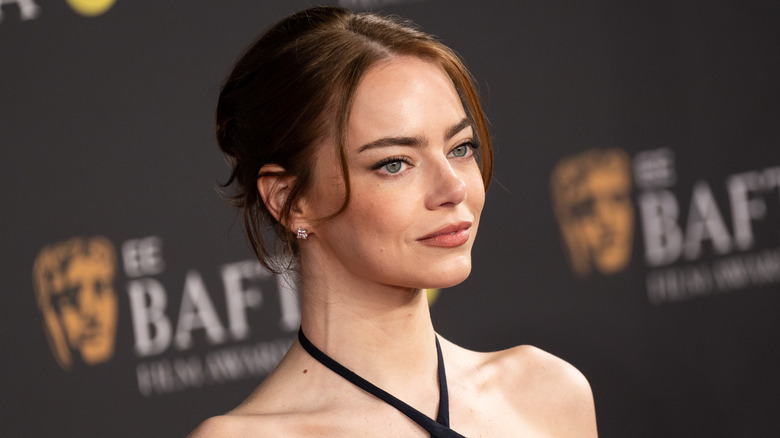 Emma Stone posing at the BAFTAs with an updo and a criss-cross neckline in black