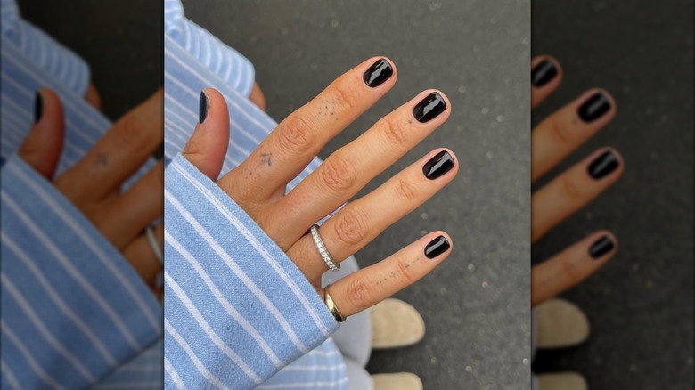 A hand with glossy black nails