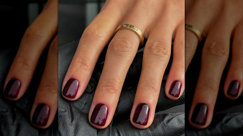 A close-up of a woman with merlot nail polish