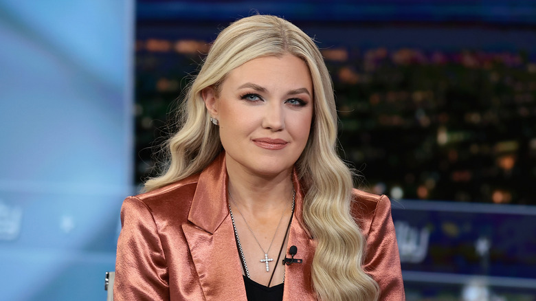 Erika Kirk looking at a camera while wearing a bronze blazer