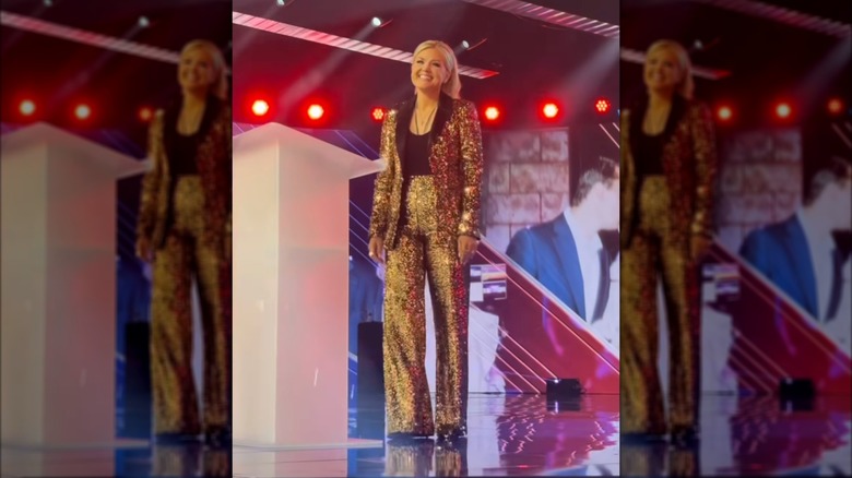 Erika Kirk on stage in a gold pantsuit