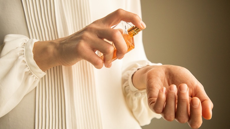 Woman applying perfume to wrists 