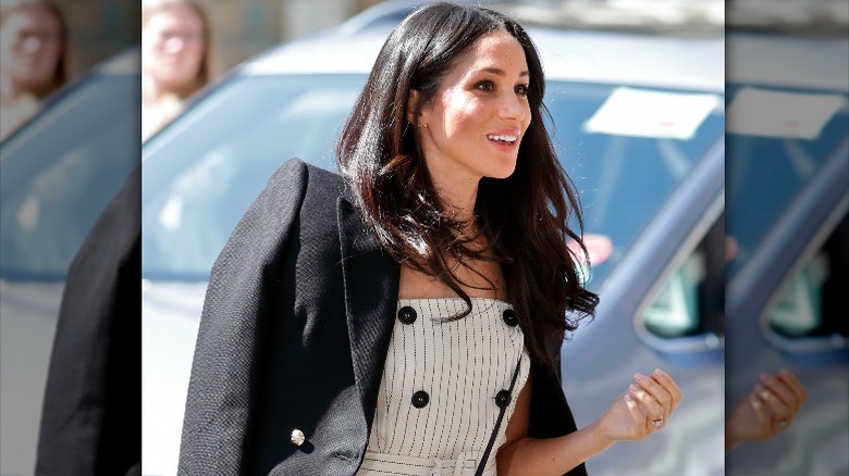 Meghan Markle enters an event in a white pinstripe dress