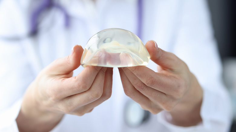 Plastic surgeon holding breast implant