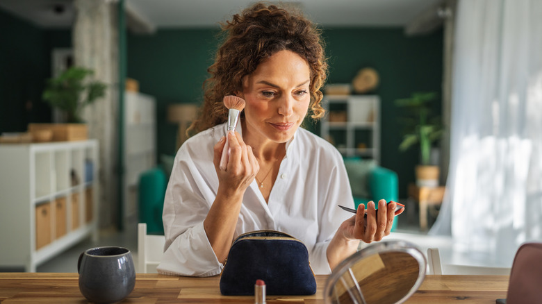Mature woman applying blush in a mirror