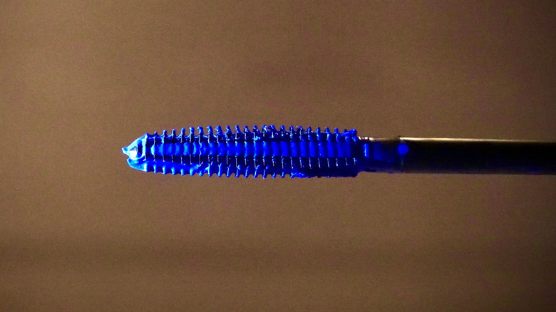 Close up of a mascara wand with blue mascara