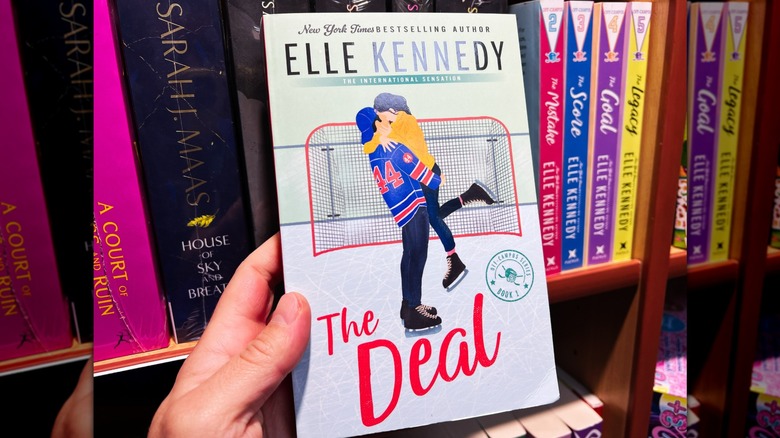 A person holds Elle Kenendy's "The Deal" in their hand