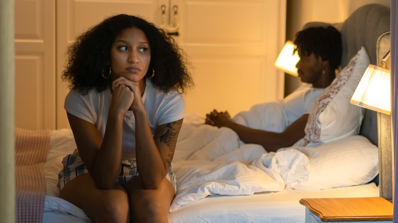 Woman sitting on bed with partner