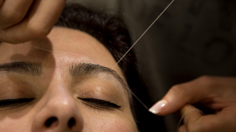 woman getting eyebrow threading