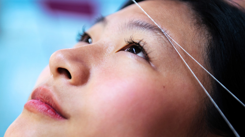 woman getting eyebrow threading
