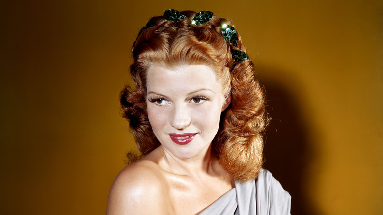 Rita Hayworth smiles with ginger hair and wearing red lipstick