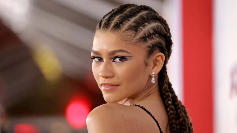 Zendaya smiles wearing braids and metallic blue and white eyeliner