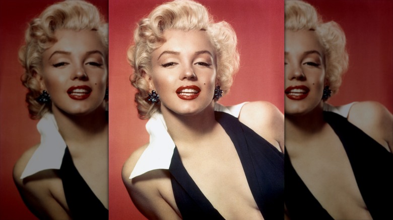 Marilyn Monroe smiles wearing red lipstick and winged eyeliner