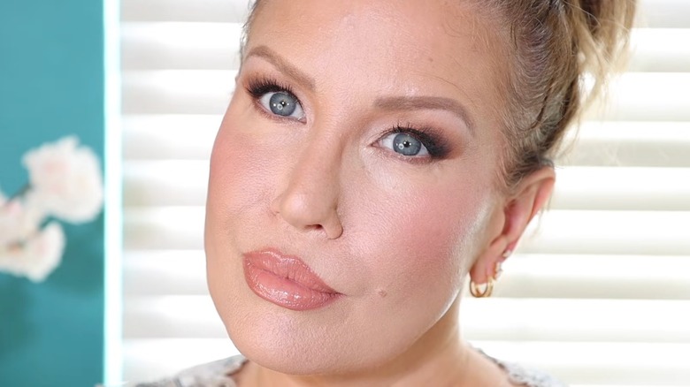 A close up of a woman with hooded eyes doing her makeup