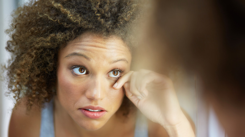 woman checks face in mirror