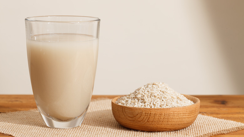 Rice water in a glass next to rice