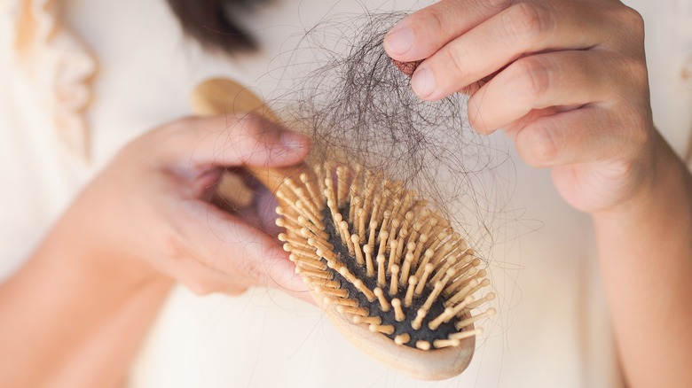 woman pulling hair from hairbrush