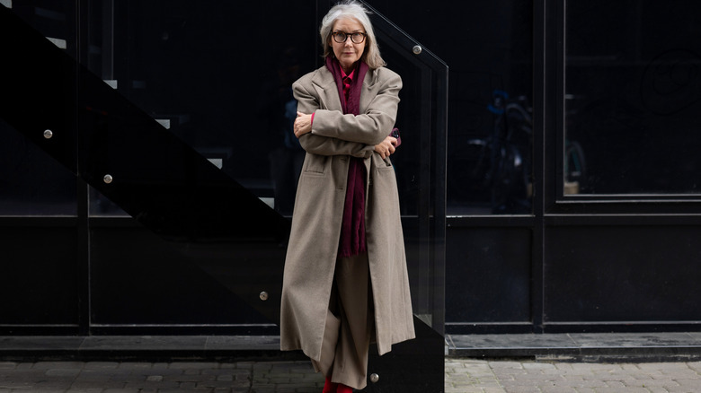 A woman in a tailored coat and plum scarf looking into camera