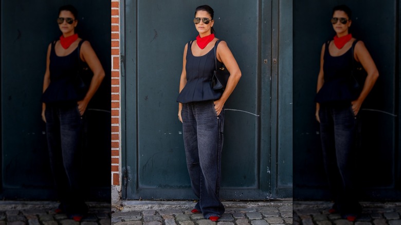 A woman on the street wearing a peplum top, red neck bandana, and dark wash baggy jeans