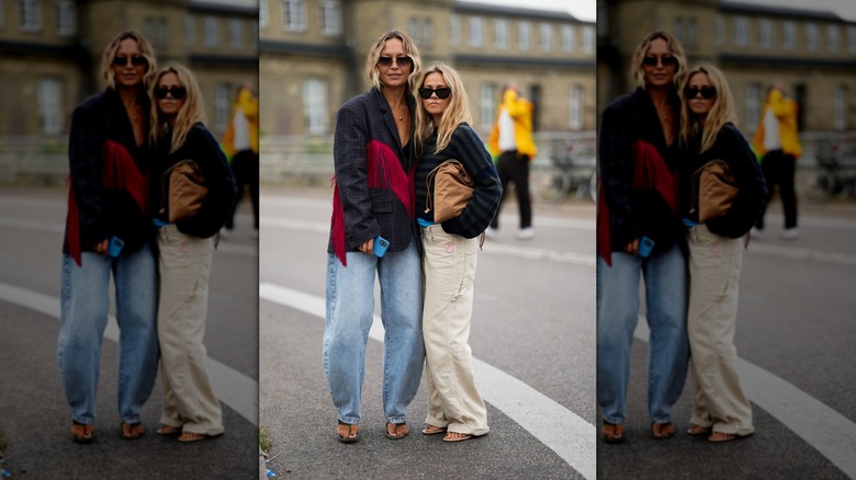 Two women on the street wearing slouchy, oversized jeans, one in light-blue and one in white