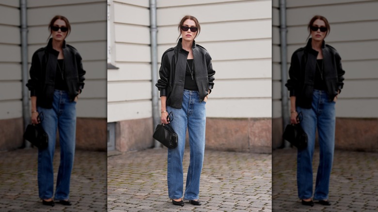 A woman standing on the street in straight-leg jeans and a leather jacket