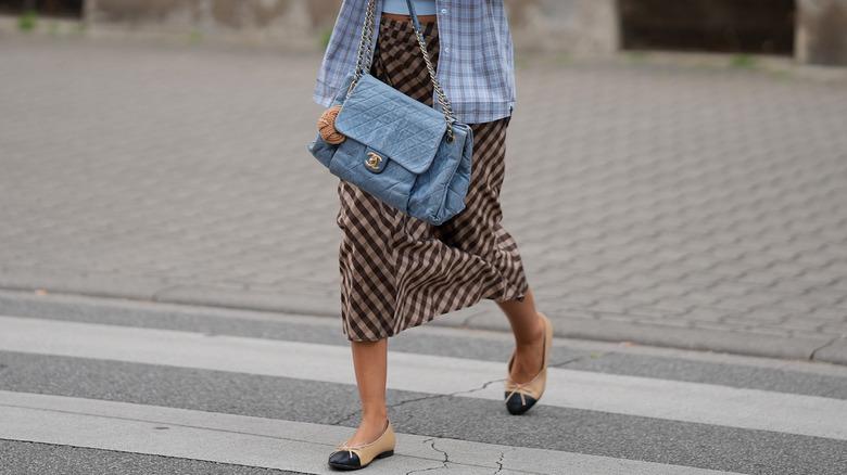 Unseen woman wearing a plaid skirt with light blue accessories and ballet flats