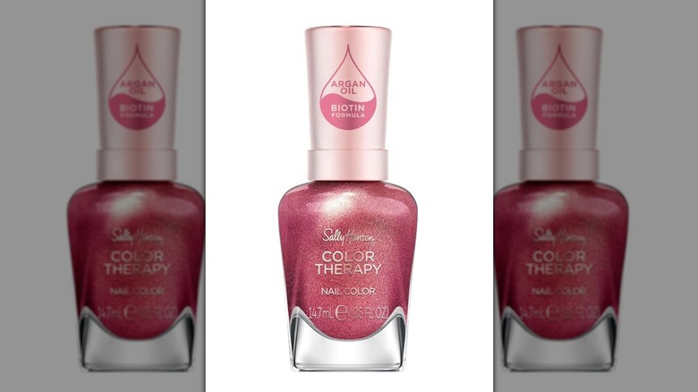 A bottle of Sally Hansen nail polish in a glittery dark pink shade
