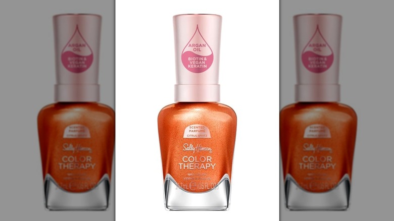 A bottle of Sally Hansen nail polish in a glittery warm orange shade