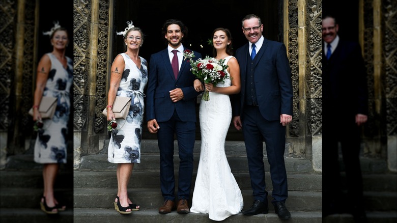 A groom and bride standing with parents at the entry of a church